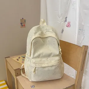 Detailansicht eines modischen cremefarbenen Rucksacks mit Sternen auf einem Holzstuhl