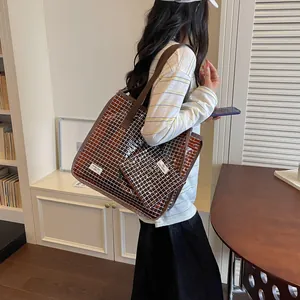Model showing the large brown grid pattern tote bag with a matching small pouch detail