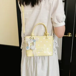 Close-up view of a yellow polka dot handbag featuring a musical note charm and lace detail.