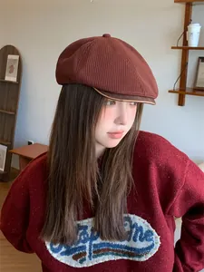 Asian woman wearing a retro terracotta knit newsboy cap in a cozy indoor setting