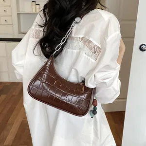 Detailed view of a stylish brown croc-embossed shoulder bag with a silver chain strap