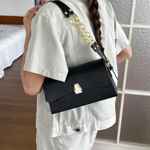 Stylish black rectangular flap bag with gold chain strap accent worn by a model