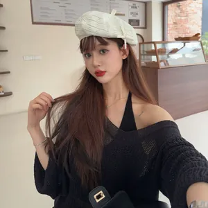 Stylish Japanese cream knit beret shown on a model in a retro cafe background detail
