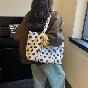 Large white polka dot tote bag with cute bear charm accessory shown on model's shoulder
