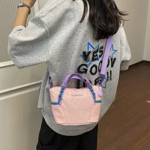 Stylish pink nylon crossbody bag with purple straps and blue accents worn by a model