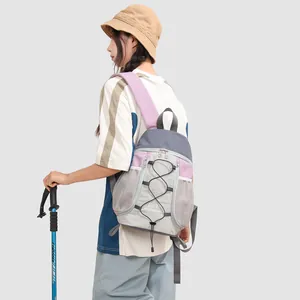 Mujer con una mochila de exterior gris y púrpura sosteniendo un bastón de trekking.
