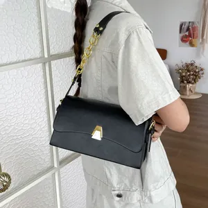Detailed view of a model wearing a black rectangular shoulder bag with gold chain strap