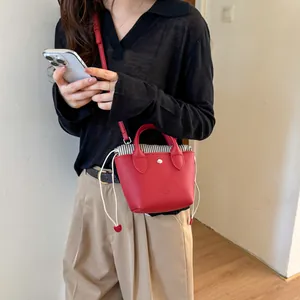 Détail d'un mini sac seau en cuir rouge avec une doublure à cordon de serrage rayé.