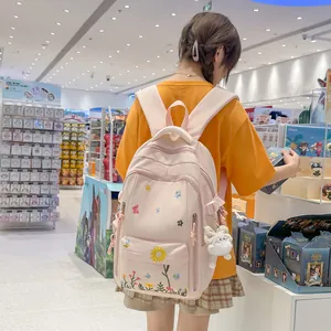 Dettaglio dello zaino rosa per studenti con ricami floreali e ciondolo di peluche