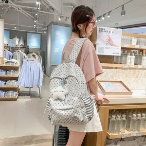 Young woman styling a casual grey star-patterned backpack with a cloud pendant in a shop.