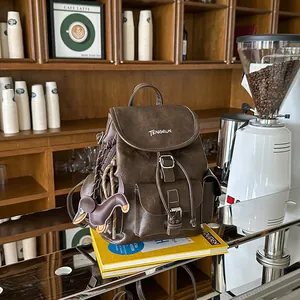 Close-up of a vintage brown faux leather backpack with a cute dog charm in a cafe