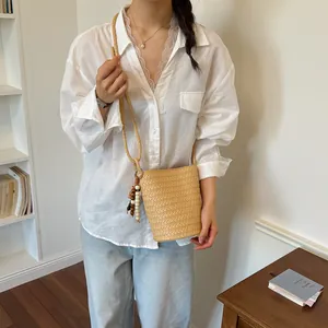 Lässige Sommer-Eimertasche gewebt mit Perlenquasten-Detail am Modell präsentiert