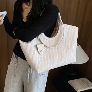 Detail shot of a white woven tote bag shown in a stylish indoor lifestyle setting