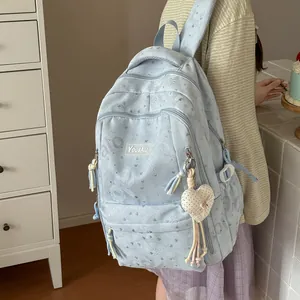 Close-up of light blue patterned backpack with heart charm and multi-pocket design