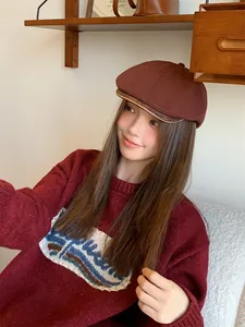 Asian model wearing a stylish burgundy knit flat cap in a cozy indoor studio setting