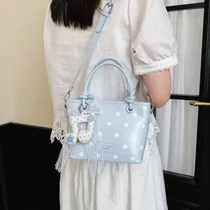 Light blue polka dot handbag with lace bow and musical note charm, shown as crossbody style.