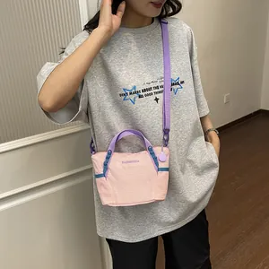Detailed view of a pink and purple crossbody fitness bag worn by a model in casual setting.