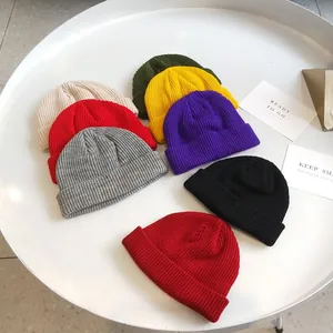 Close-up view of various colorful ribbed knit short beanies displayed on a white round table
