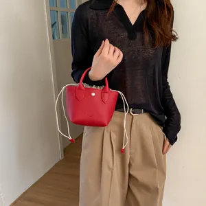 Vue détaillée d'un mini sac seau rouge avec fermeture par cordon et poignée supérieure élégante