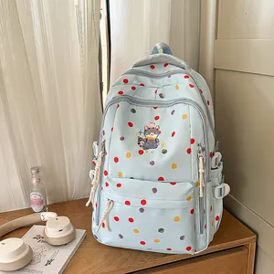 Primo piano di uno zaino azzurro a pois con un simpatico dettaglio di ricamo a gatto.