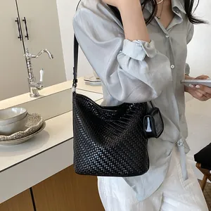 Close-up detail of a stylish black woven leather bucket bag for women in a kitchen.
