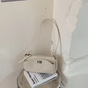 Gros plan élégant d'un sac baguette beige minimaliste avec fermoir métallique argenté
