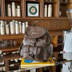 Vintage brown faux leather backpack with multiple buckled pockets in a cafe setting