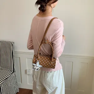 Back view of model wearing a chic brown polka dot barrel bag with a silver star charm