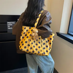 Back view of a large yellow polka dot tote bag featuring a cute teddy bear charm