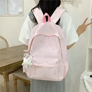 Detailed view of the pink floral backpack worn by a student in an indoor setting