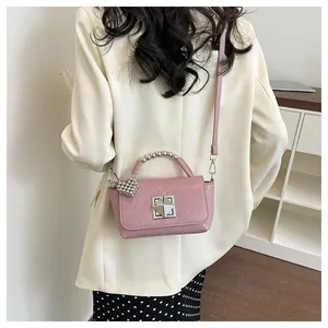 Back view of a model wearing a pink square crossbody bag with a silver beaded handle.