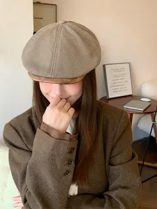 Close-up of a woman wearing a stylish retro khaki knitted newsboy hat in an autumn setting