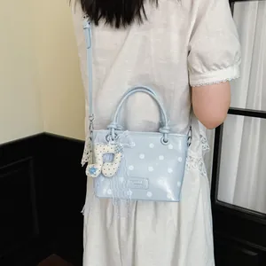 Detailed view of light blue polka dot handbag with music note charm and lace accessory