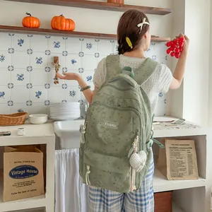 Back view of woman wearing a green heart-print backpack in a lifestyle kitchen setting