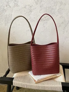 Bolsos de cubo tejidos minimalistas en granate y color caqui sobre una silla