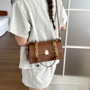 Detailed view of the brown leather crossbody bag with elegant gold chain handle.