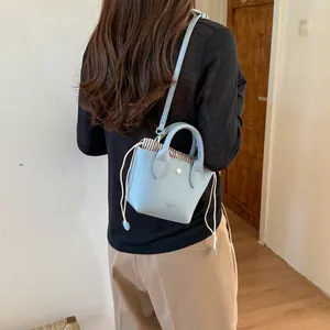 Vue détaillée d'un mini sac seau en cuir bleu clair portant la marque Parisa London