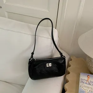 Sac baguette texturé noir élégant placé sur un canapé blanc dans un décor de vie