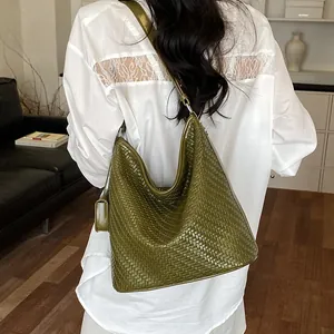 Stylish green woven hobo bag shown from the back on a model wearing a white lace shirt