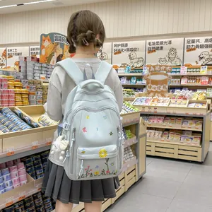 Zaino scolastico azzurro per studenti con ricami floreali e simpatico ciondolo.