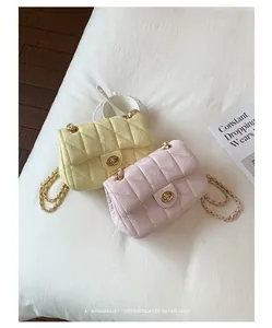 Detailweergave van elegante gewatteerde crossbodytassen in geel en roze met kettingen.