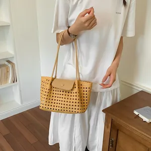 Frau im weißen T-Shirt trägt eine große beige gewebte hohle Tragetasche im Zimmer