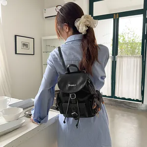 Stylish black niche design backpack with TENGRUN logo worn by a model in a cafe setting.