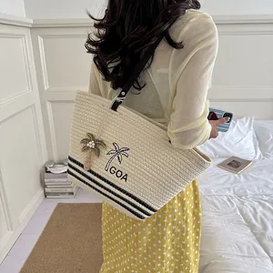 Detailansicht der gewebten Strohtasche für Damen mit Palmenstickerei und schwarzen Streifen
