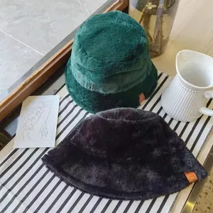 Detail view showing the soft plush texture of green and black winter furry bucket hats