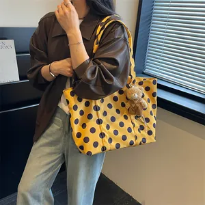 Yellow polka dot tote bag with bear charm detail shown on a model for daily commute