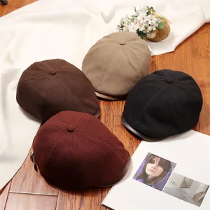 Group of vintage knitted newsboy caps in various colors on wooden floor with accessories.