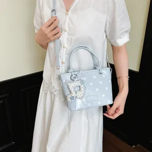 Macro view of light blue polka dot crossbody bag featuring a decorative musical note charm.