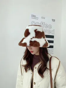 Close-up of a stylish cow-print plush bucket hat worn by a model in winter
