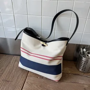 Detailed view of a striped canvas tote bag with red and blue stripes and a toggle closure